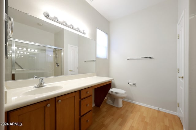 bathroom with vanity, toilet, hardwood / wood-style floors, and a shower with door