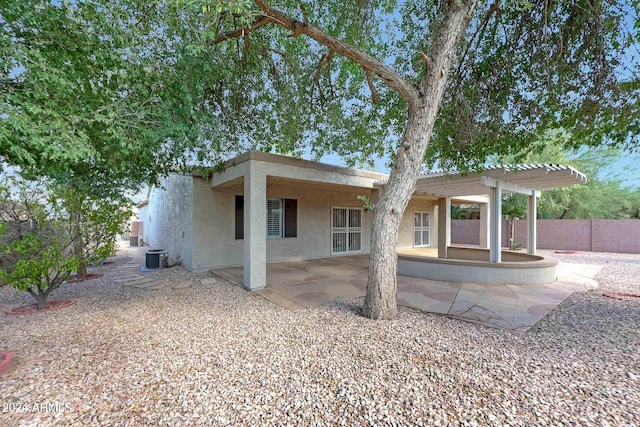 rear view of property with central air condition unit, a patio area, and a pergola