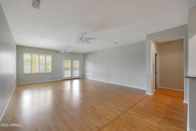 unfurnished room with ceiling fan, light wood-type flooring, and french doors