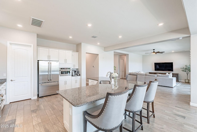 kitchen featuring a kitchen bar, visible vents, stainless steel appliances, and a sink