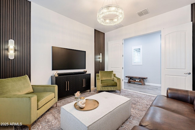 living room with baseboards, visible vents, a notable chandelier, and wood finished floors