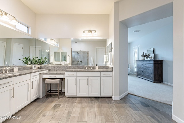 full bathroom featuring a sink, visible vents, a tile shower, and wood finished floors