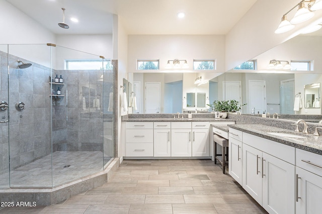 full bath featuring two vanities, a sink, and a shower stall