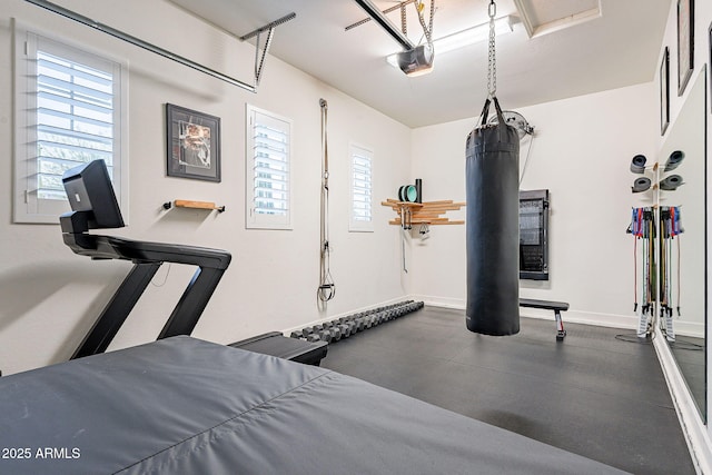 exercise area with a garage, a wealth of natural light, and baseboards