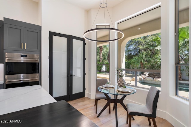dining area with a healthy amount of sunlight, baseboards, french doors, and light wood-style flooring