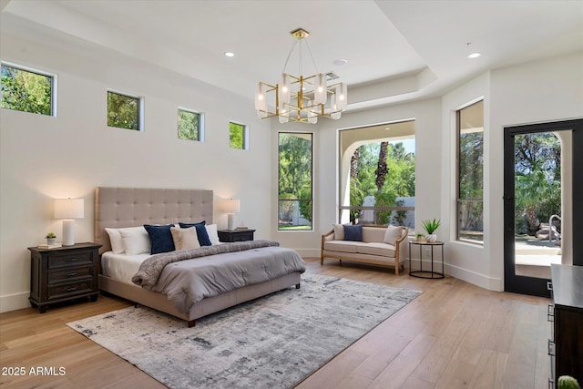 bedroom featuring an inviting chandelier, multiple windows, and light wood-style floors