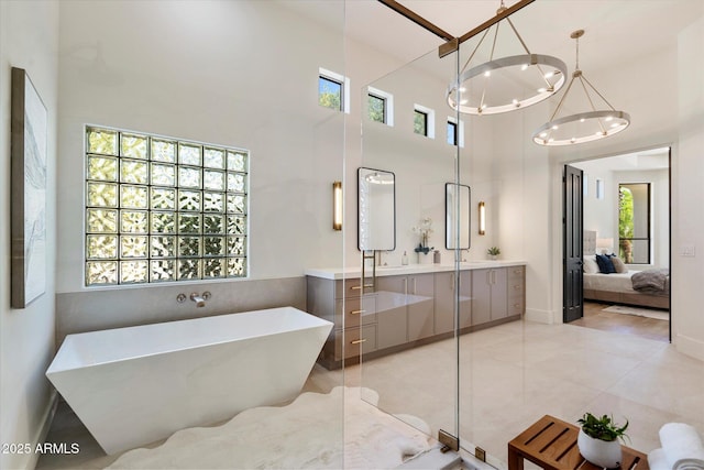 full bath with vanity, a chandelier, a freestanding tub, ensuite bathroom, and a towering ceiling