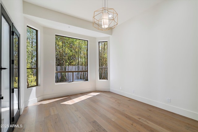 unfurnished dining area with baseboards, wood-type flooring, and a wealth of natural light