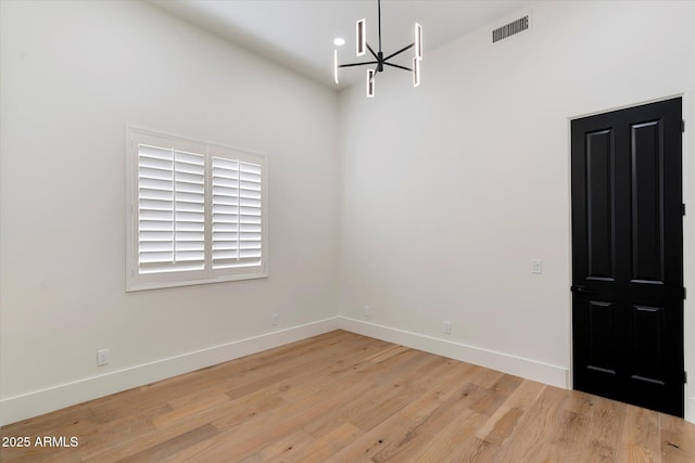 unfurnished room with baseboards, a chandelier, light wood-style flooring, and visible vents