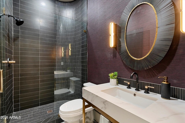 full bathroom featuring vanity, a tile shower, and toilet