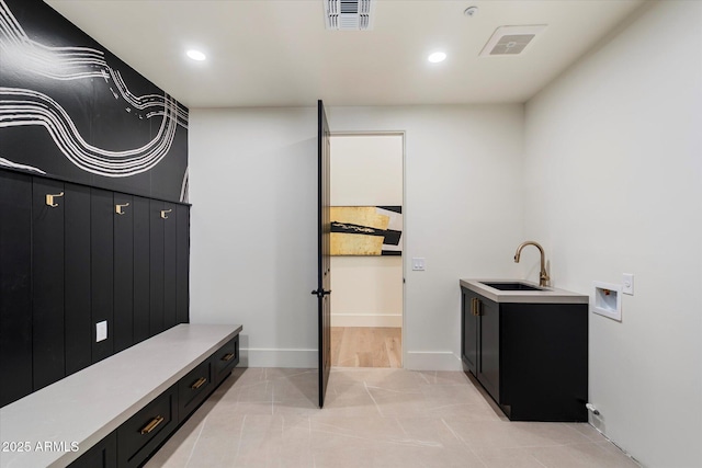 interior space featuring cabinet space, a sink, hookup for a washing machine, light tile patterned floors, and visible vents