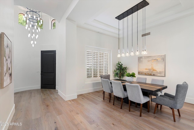 dining room featuring an inviting chandelier, baseboards, wood finished floors, and a tray ceiling