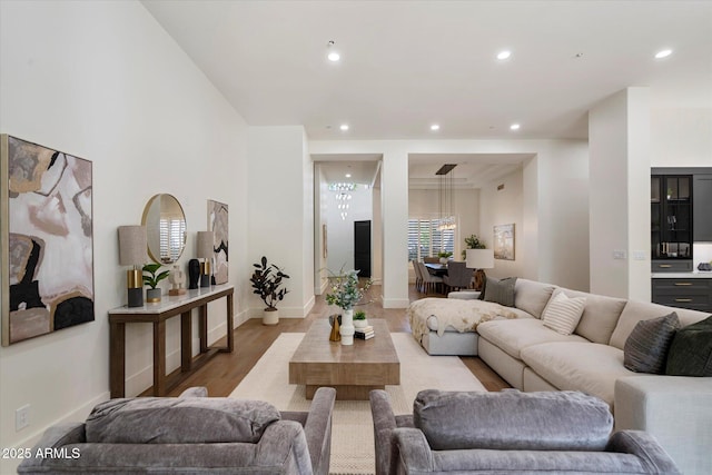 living room with recessed lighting, baseboards, an inviting chandelier, and wood finished floors