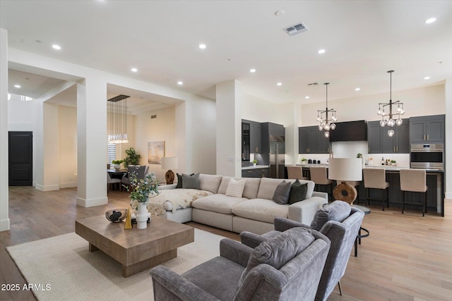 living room with recessed lighting, a notable chandelier, light wood finished floors, and visible vents