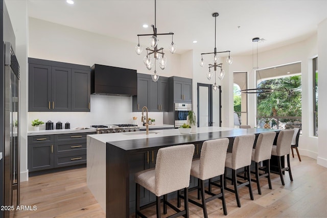 kitchen with decorative backsplash, a high ceiling, wall chimney exhaust hood, a sink, and stainless steel appliances