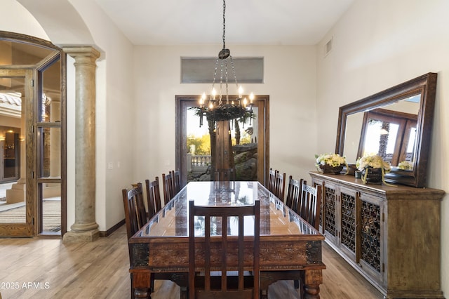 dining room featuring decorative columns, hardwood / wood-style floors, and a chandelier