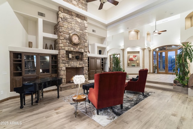 interior space featuring a high ceiling, a stone fireplace, light wood-type flooring, and ceiling fan