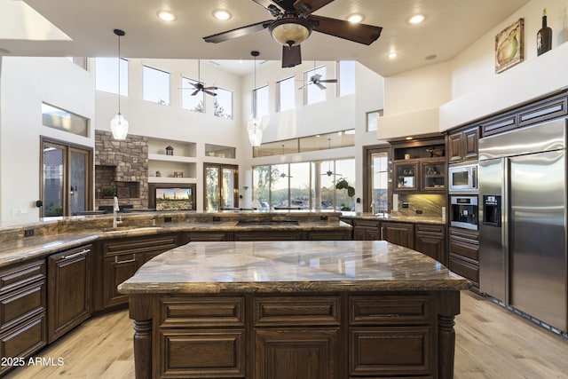 kitchen featuring a towering ceiling, built in appliances, a center island, and sink