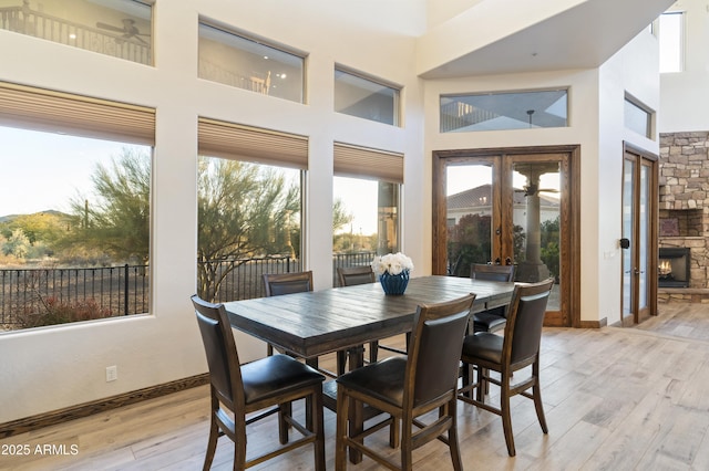 dining space featuring a towering ceiling, a fireplace, and light hardwood / wood-style floors