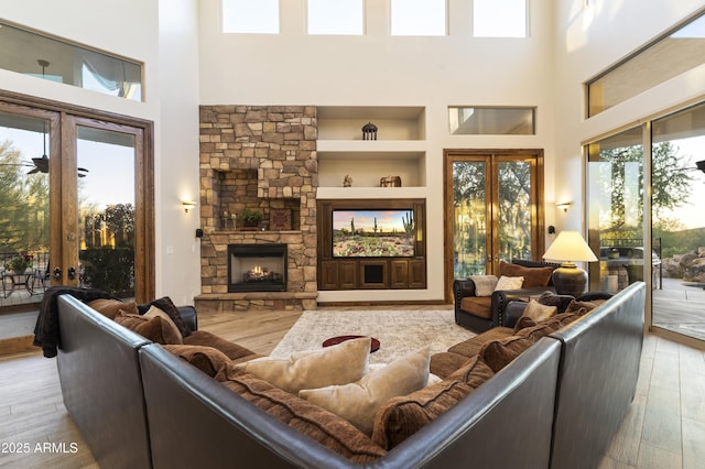 living room featuring built in shelves, a fireplace, french doors, and a wealth of natural light