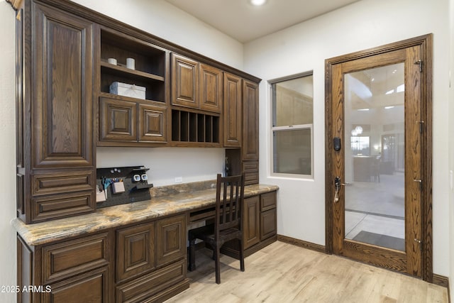 home office with light hardwood / wood-style flooring and built in desk