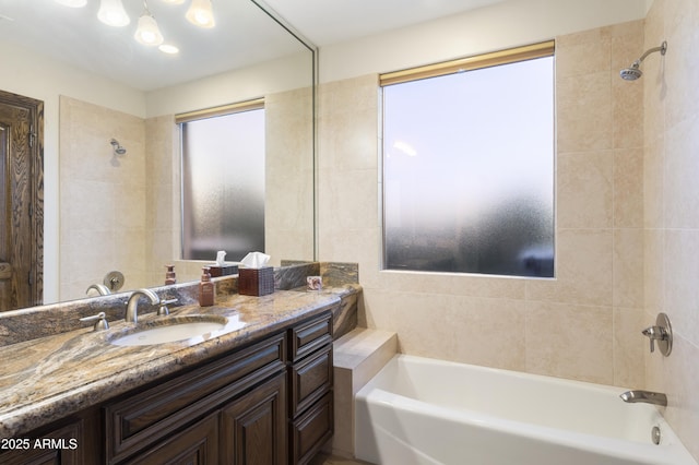 bathroom featuring a healthy amount of sunlight, tiled shower / bath, and vanity