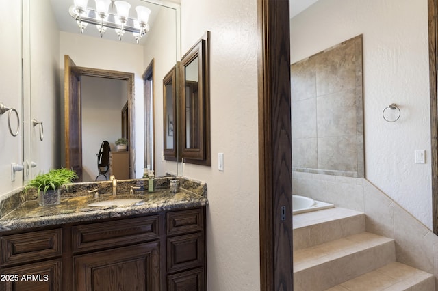 bathroom with tiled tub and vanity