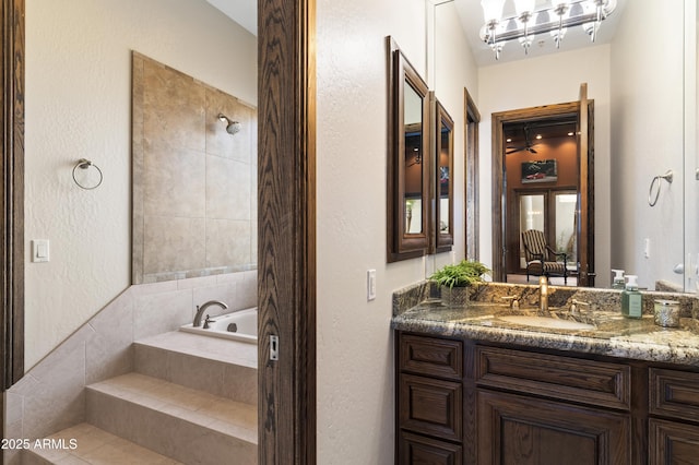 bathroom featuring vanity and a relaxing tiled tub