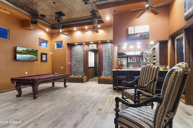 playroom with pool table, bar, light hardwood / wood-style flooring, and a high ceiling