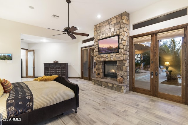 bedroom with a fireplace, access to outside, ceiling fan, and light wood-type flooring