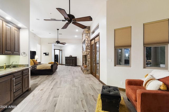 living room featuring ceiling fan, sink, and light wood-type flooring