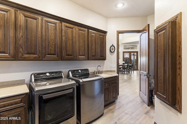 washroom with sink, cabinets, light hardwood / wood-style floors, and independent washer and dryer