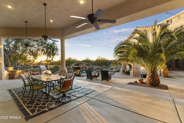 patio terrace at dusk with ceiling fan and an outdoor kitchen