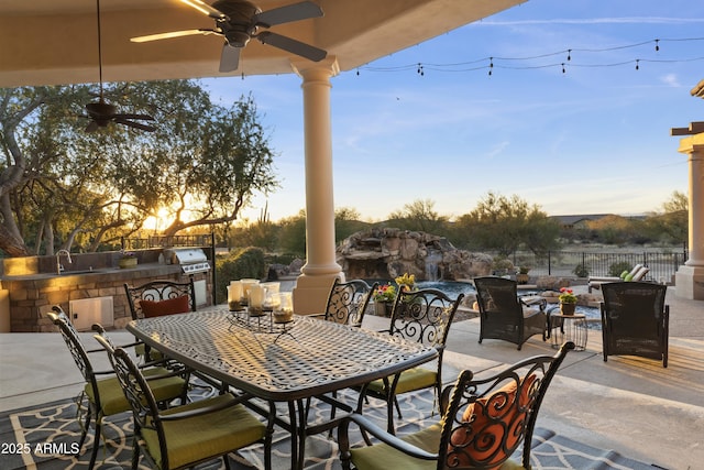 patio terrace at dusk featuring an outdoor kitchen and ceiling fan