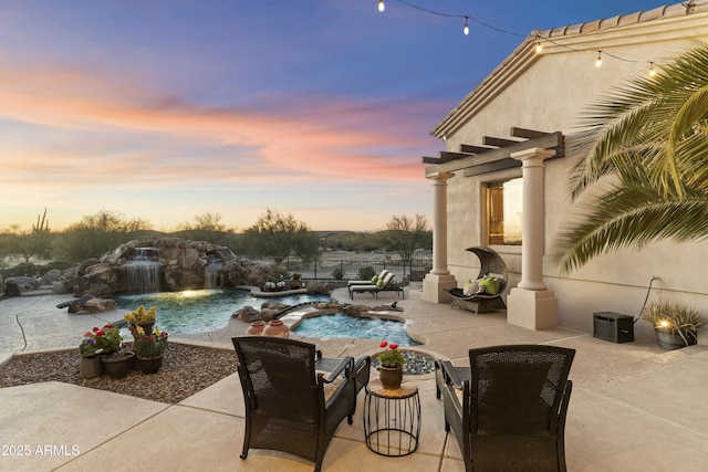 pool at dusk featuring a patio, pool water feature, and a pergola