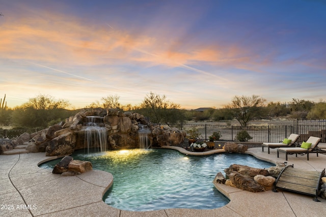 pool at dusk with a patio area and pool water feature