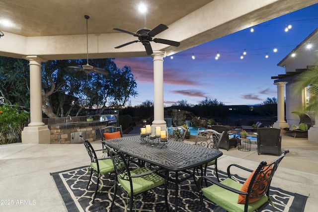 patio terrace at dusk featuring a bar and ceiling fan