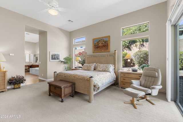 carpeted bedroom with ensuite bathroom and ceiling fan