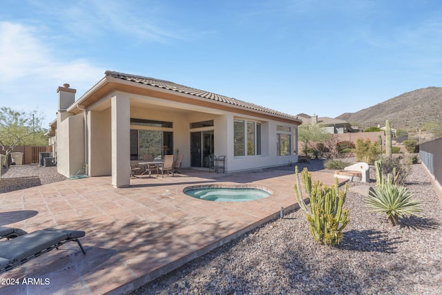 back of property with a patio, a mountain view, and an in ground hot tub