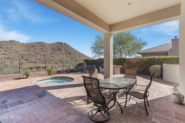 view of patio featuring a mountain view and an in ground hot tub