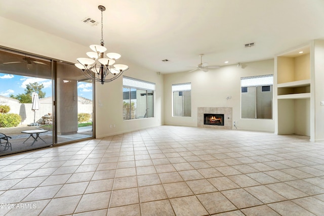 unfurnished living room featuring light tile patterned flooring, a tiled fireplace, ceiling fan with notable chandelier, and built in features