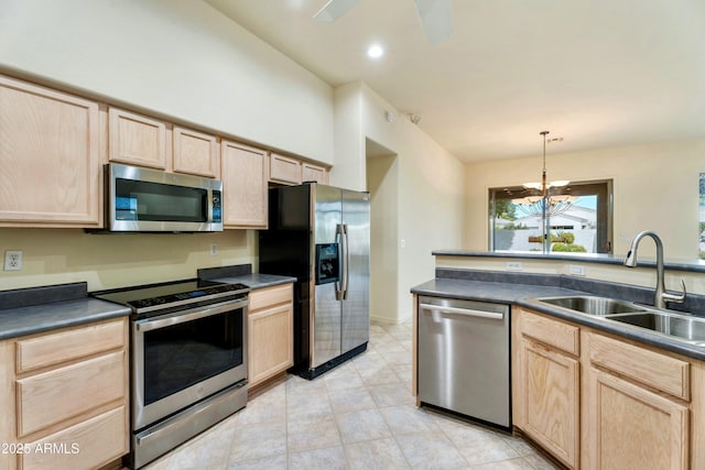 kitchen featuring light brown cabinetry, sink, appliances with stainless steel finishes, pendant lighting, and ceiling fan with notable chandelier