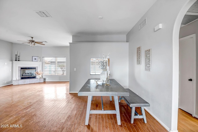 10215 W Missouri Ave, Glendale, AZ 85307 - dining area featuring ceiling fan, arched walkways, wood finished floors, a tile fireplace, and baseboards