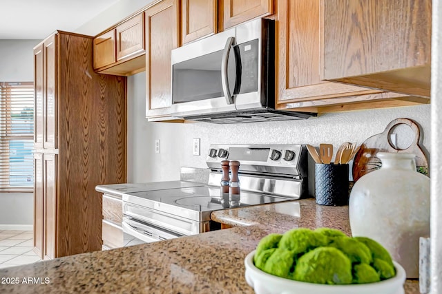 10215 W Missouri Ave, Glendale, AZ 85307 - kitchen featuring stainless steel appliances, light tile patterned floors, light stone counters, and brown cabinetry