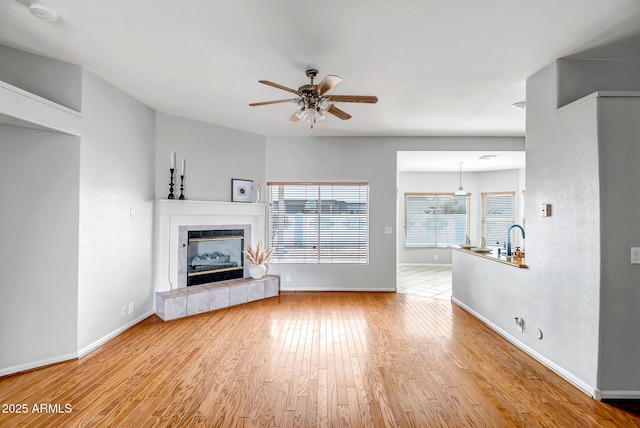 10215 W Missouri Ave, Glendale, AZ 85307 - unfurnished living room featuring ceiling fan, wood finished floors, baseboards, and a tiled fireplace