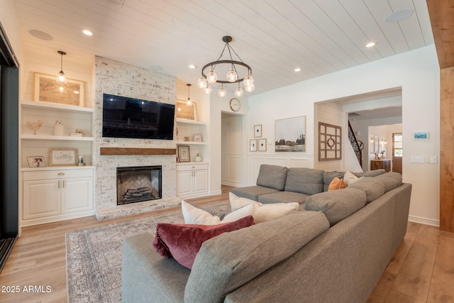 living area featuring built in features, light wood-style flooring, wood ceiling, stairs, and a stone fireplace