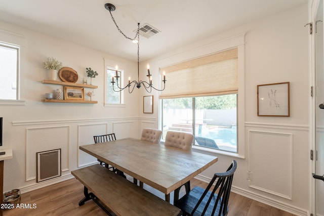 dining area featuring a chandelier, a decorative wall, and wood finished floors