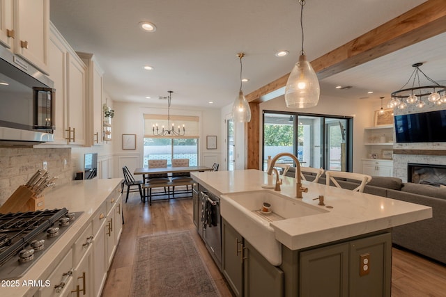 kitchen featuring appliances with stainless steel finishes, a sink, a chandelier, wood finished floors, and recessed lighting