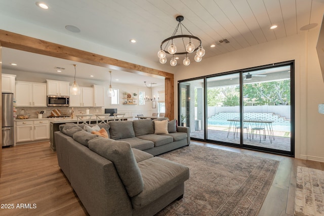 living room featuring recessed lighting, a chandelier, wood finished floors, and beamed ceiling