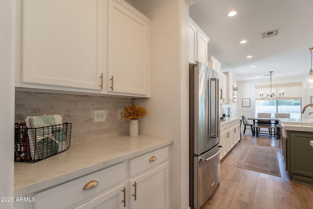 kitchen featuring high quality fridge, white cabinetry, recessed lighting, light wood finished floors, and a chandelier
